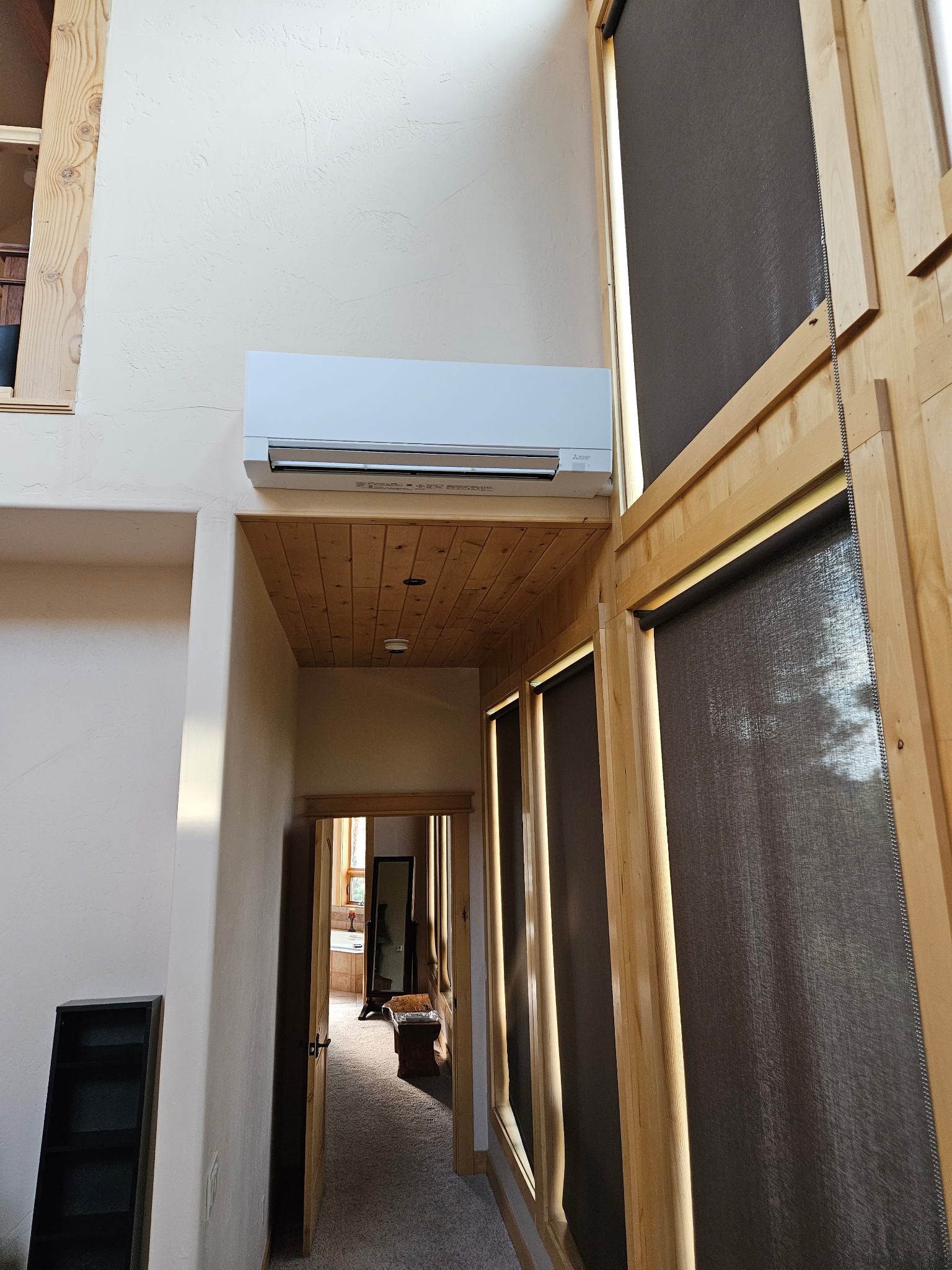 Mini-split indoor unit mounted above a wood-trimmed hallway in a modern mountain home